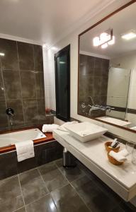 萨尔塔MG Design Hotel Boutique的一间带水槽、浴缸和镜子的浴室
