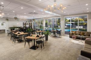 陶朗加阿米蒂奇酒店及会议中心的一间设有桌椅的餐厅,位于带窗户的房间内