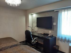 伊万里市HOTEL WIN的一间卧室配有一张桌子、一台电视和一张床
