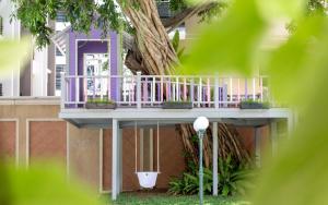 芭堤雅市中心The Bayview Hotel Pattaya的树旁有紫色甲板的房子