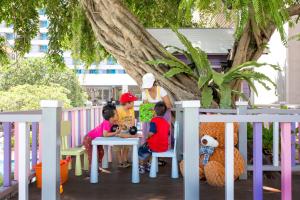 芭堤雅市中心The Bayview Hotel Pattaya的一群坐在树下桌子上的孩子