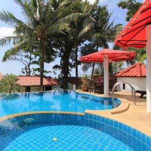 象岛顶级度假酒店的一个带红色遮阳伞和棕榈树的大型游泳池