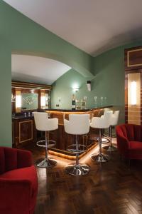 布莱顿霍夫Sea-facing Art Deco Apartment的一间设有白色凳子的酒吧,位于一间设有绿色墙壁的房间