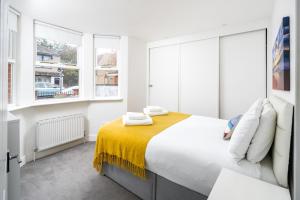 伦敦Stunning 2-bed flat w/ garden patio in West London的白色卧室设有大床和窗户
