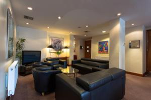 布拉姆霍普大不列颠利兹布拉福德机场酒店的客厅配有黑色皮革家具和电视