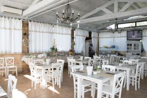 朱尔迪尼亚诺贝拉里亚公寓酒店的用餐室配有白色的桌子和白色的椅子