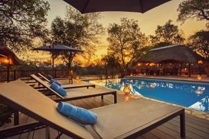 侯斯普瑞特Vuyani River Lodge的毗邻度假酒店的带桌子和遮阳伞的游泳池
