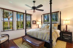 科洛阿The Lodge at Kukuiula - CoralTree Residence Collection的一间卧室配有一张带吊扇和窗户的床。