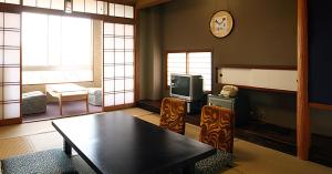 涩川市伊香保银水酒店的客厅配有桌子和电视