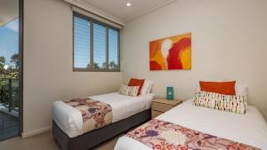 马库拉White Shells Luxury Apartments Marcoola的带窗户的客房内的两张床