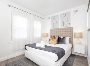 悉尼The Great Escape Bellevue Hill的白色卧室设有一张大床和两个窗户