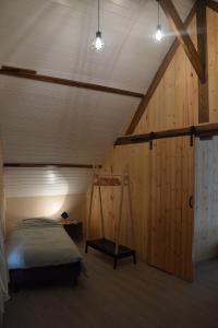 MaarkedalDe Bossenaarshoeve的一间卧室设有一张床和木墙