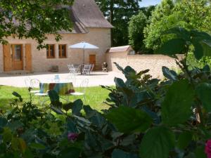FleuracMaison Périgord Noir près de Lascaux, Montignac, Sarlat, Périgueux的房屋前设有带桌子和遮阳伞的花园