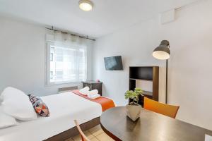 托农莱班Appart'City Classic Thonon Les Bains的酒店客房配有床、桌子和桌子。