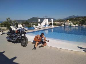 卢什蒂卡Luštica Apartments的手持吉他,坐在游泳池旁的摩托车旁