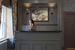 马里卡尔特玛丽卡特之家酒店的一名妇女在柜台后面用手机说话