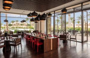 托泽尔Anantara Sahara-Tozeur Resort & Villas的餐厅设有桌椅和大窗户。