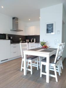 鲁斯特Boland Apartments的白色的厨房配有白色的桌子和椅子