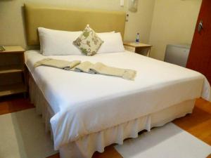 乌姆塔塔Lilliz Guest House的一张大白色的床,位于带两张桌子的房间