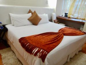 乌姆塔塔Lilliz Guest House的卧室配有白色的床,上面有橙色毯子