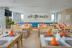 岘港Cordial Hotel and Spa的用餐室配有桌椅和橙色餐巾