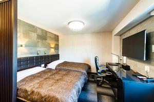 伊万里市HOTEL WIN的酒店客房设有一张床、一张书桌和一台电视机。