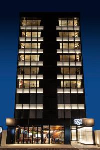 熊本Place Hotel Ascot的一座黑高楼,晚上有很多窗户