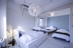 东京STAY ARI Arakicho的一间白色卧室,配有两张床和吊灯
