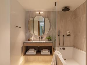 伦敦The Stratford Hotel London的一间带水槽、浴缸和镜子的浴室
