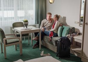 巴德加斯坦Hotel Goethehof的坐在酒店房间沙发上的男人和女人
