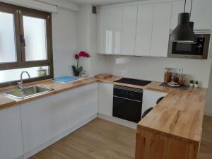 奥维多Apartamento LOS VEGA- parking privado的厨房配有白色橱柜和木制台面