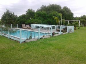 圣何塞La Rosa del Azafrán - Alojamiento Rural - Ranchos de Vacaciones en Entre Ríos的草地旁边的游泳池,带蓝色栏杆