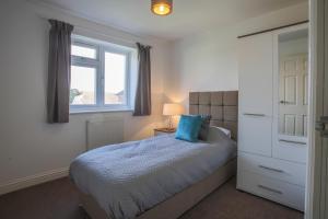 NorthfleetVale House的一间卧室配有一张带蓝色枕头的床和窗户