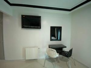 突尼斯Hôtel le calife的一间设有两把椅子、一张桌子和一台电视的房间