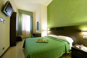 米兰伊德亚雷酒店的酒店客房,配有一张绿色的床,上面有水果盘