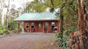 沃尔卡诺Alii Kane Cottages with Loft的树林中带绿色屋顶的红色小屋