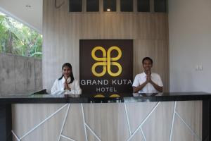 龙目岛库塔Grand Kuta Hotel的两个人站在酒店标志前