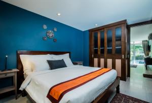 卡伦海滩Kata Tranquil Villa - SHA Plus的一间卧室配有一张带蓝色墙壁的大床