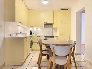 锡永Apartment Del Sol Sion Center的厨房配有黄色橱柜和木桌及椅子