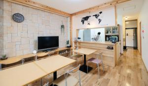 鸟取市Tottori Guest House Miraie BASE的一间设有桌子、电视和墙壁的房间