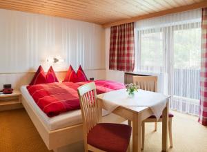 布利克森塔勒Gästehaus Hofer的一间卧室配有一张红色的床、一张桌子和一张桌子。
