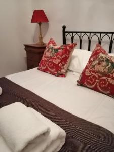 斯卡伯勒Crown Spa Apartment 13的一张带红色枕头的床和白色毛巾