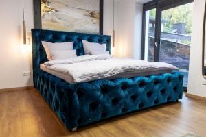 科赫姆IchZeit Aparthotel的一张床上,上面有一个蓝色的簇绒床头板