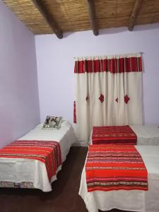 蒂尔卡拉La Posada de Bartola的一间卧室设有两张床,窗户配有窗帘