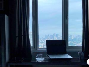 马尼拉Modern Place of Style的坐在窗前的桌子上的笔记本电脑