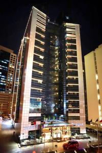 迪拜金色郁金香媒体酒店 的一座大型建筑,在晚上有车在前面