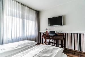 巴特恩豪森斯蒂克德普里瓦酒店的一间卧室配有一张床、一张书桌和一台电视