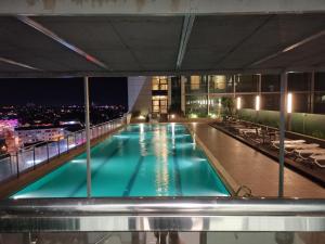 古晋贝尔纳德2号度假屋 - 古晋帝国大道套房的一座游泳池,在晚上在一座建筑的顶部