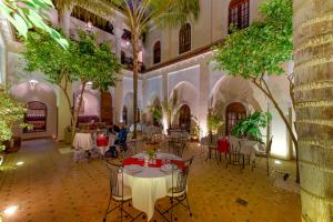 马拉喀什里亚德阿米娜酒店的树木繁茂的建筑里,设有桌椅的房间