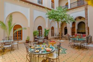 马拉喀什里亚德阿米娜酒店的大楼内带桌椅的庭院